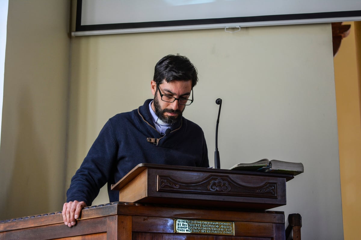 Focused male lecturer reading report on tribune with microphone